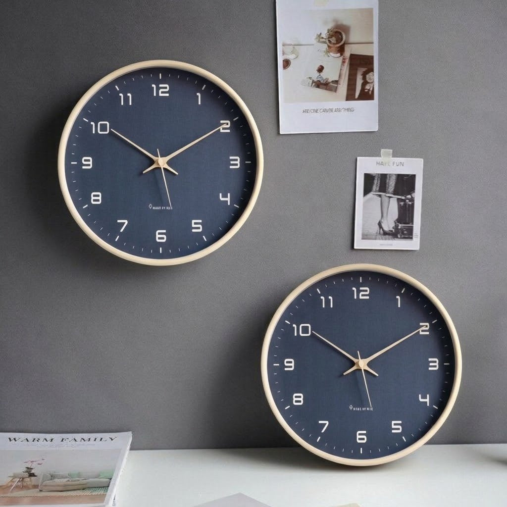Two navy blue wall clocks with pale wood frames on a dark gray wall above a white desk
