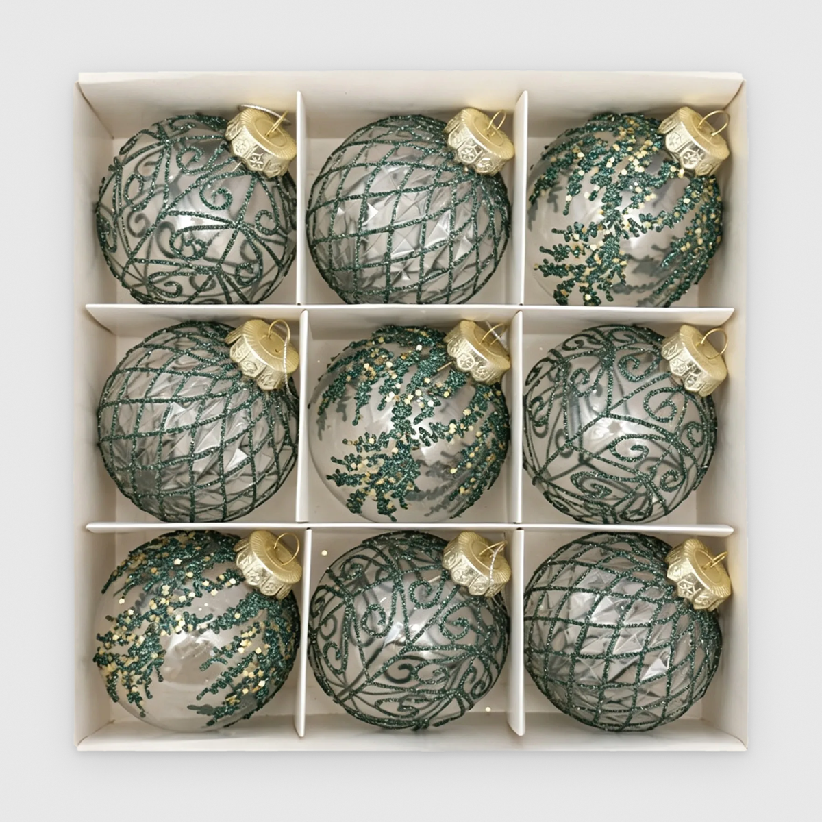 Box of 9 clear Christmas baubles with green glitter scroll, lattice and frond designs and gold caps