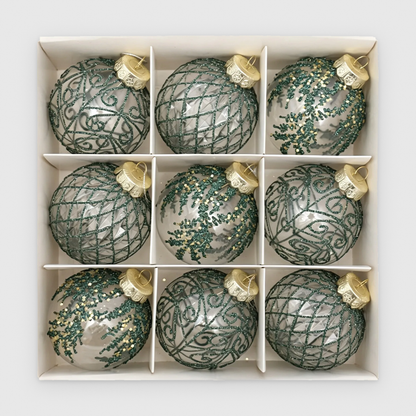Box of 9 clear Christmas baubles with green glitter scroll, lattice and frond designs and gold caps