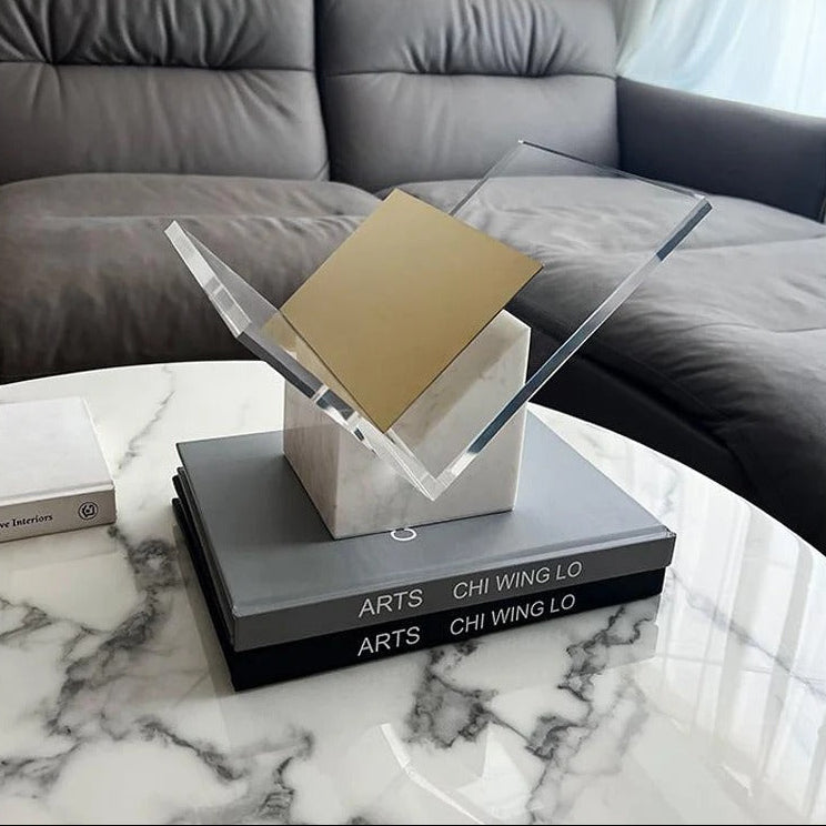 White marble magazine holder with its gold-toned divider on a marble coffee table in front of a gray sofa