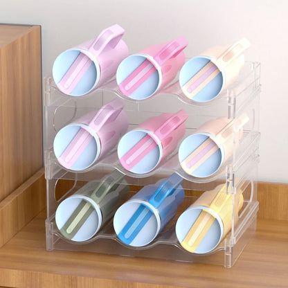 A clear three-tier bottle rack holding nine handled tumblers on their sides, on a wooden sideboard.