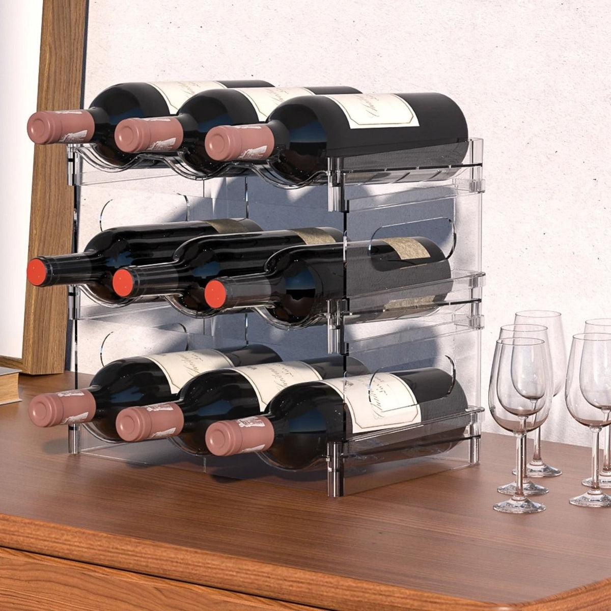 A clear three-tier rack holding nine bottles of red wine lying flat on a walnut sideboard beside wine glasses.