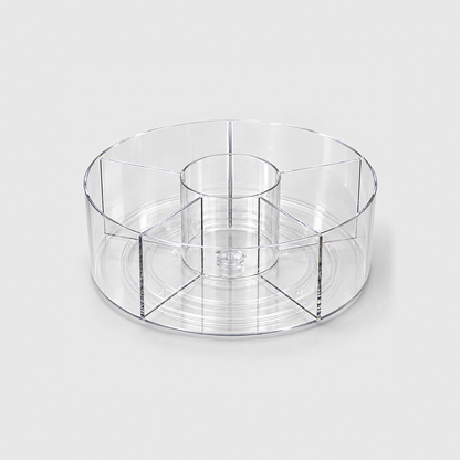 A clear round lazy Susan with a center cup and five divided sections, empty on a light grey background.