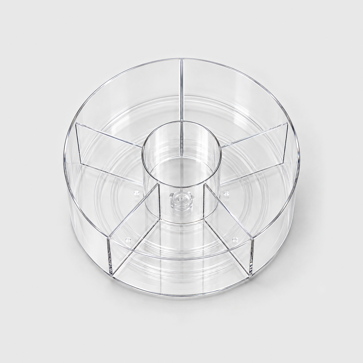 A clear divided lazy Susan seen from above, showing the center cup and the five sections around it.