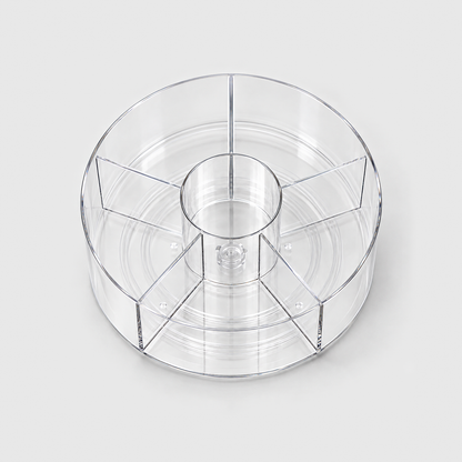 A clear divided lazy Susan seen from above, showing the center cup and the five sections around it.