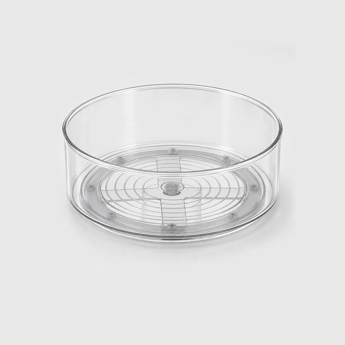 A clear round lazy Susan turntable, empty, on a light grey background, with its grey turning base visible through the clear floor.