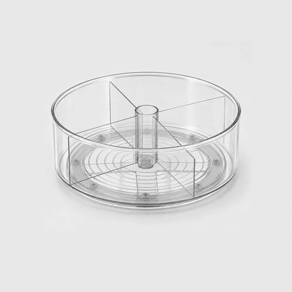 A clear round lazy Susan with four divider panels around a hollow center post, empty, on a light grey background.