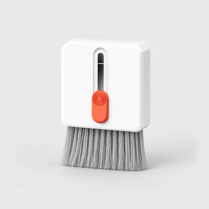 A white keyboard cleaning brush with an orange slider and gray bristles pushed out, on a light gray background.