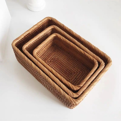 Three rattan storage baskets nested one inside the next on a white surface