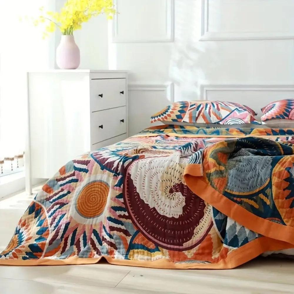 Sunburst blanket on a bed with one corner folded back to show the navy and slate gray reverse