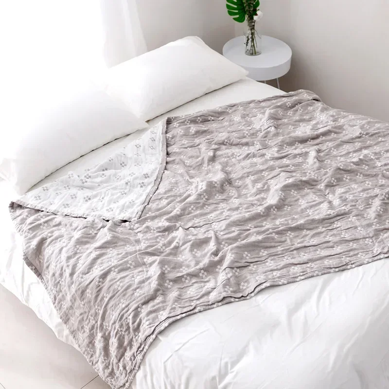 Gray diamond dot blanket laid over a white bed, gently crinkled, one corner turned back to show the cream reverse