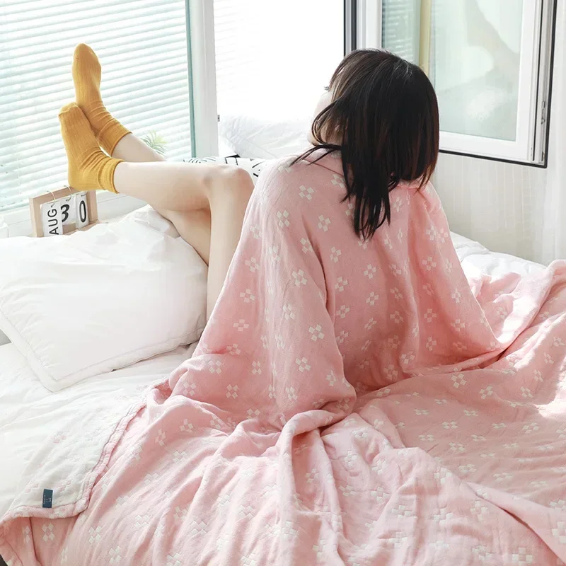 Pink diamond dot cotton blanket wrapped around a person sitting on a bed by a window