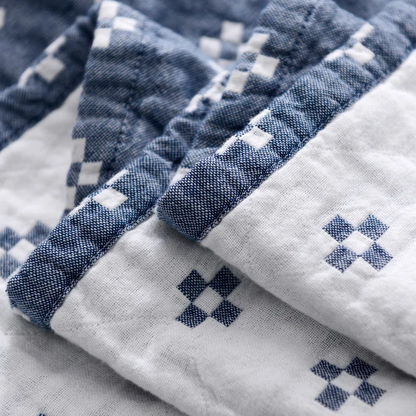 Close-up of the blue blanket's bound edge, white diamonds on blue beside blue diamonds on cream