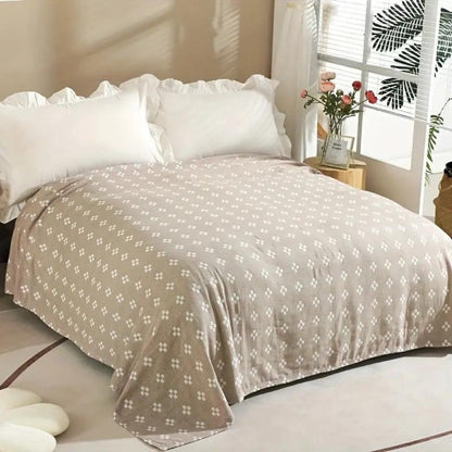Khaki diamond dot cotton blanket spread over a bed, white diamonds on a soft beige-brown ground