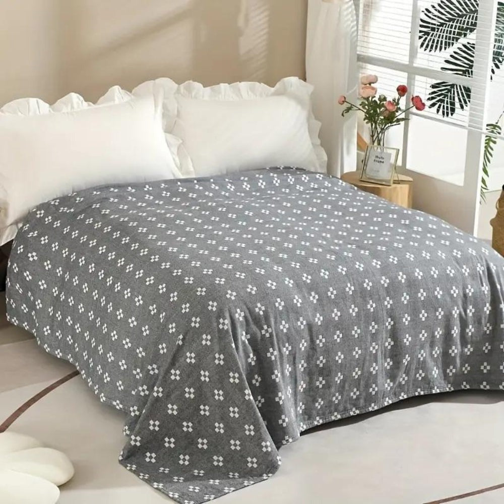 Charcoal diamond dot cotton blanket spread over a bed, white diamonds on a deep gray ground