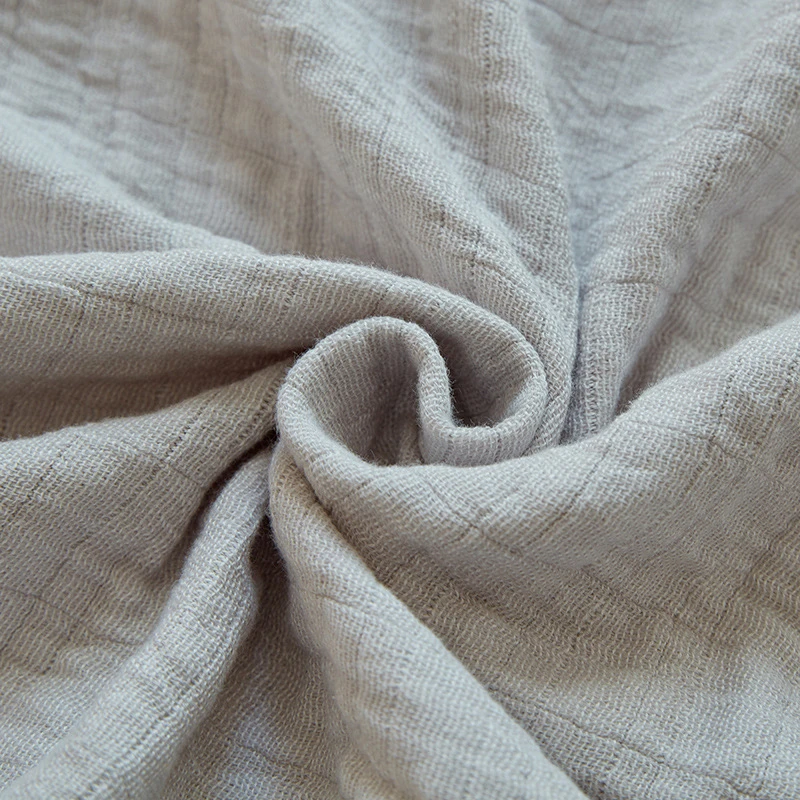 Close-up of gray cotton muslin twisted into a swirl, showing the crinkled gauze and its fine grid of lines