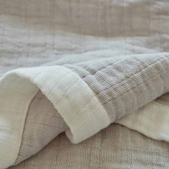 Close-up of a folded corner showing the wide white band wrapped over both faces of the muslin