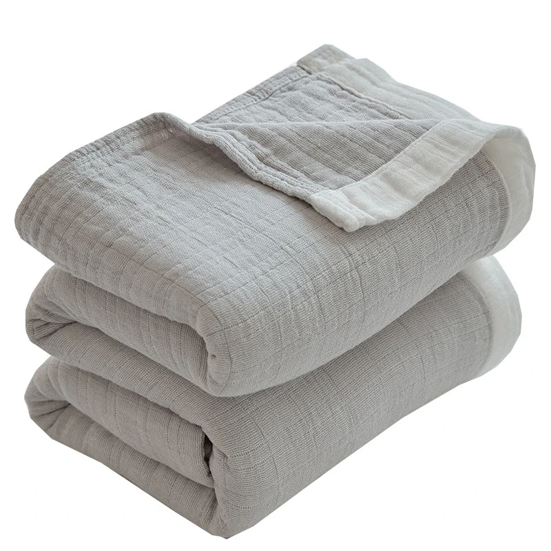 Gray muslin cotton blanket folded in a stack, one corner turned back to show the white edge band
