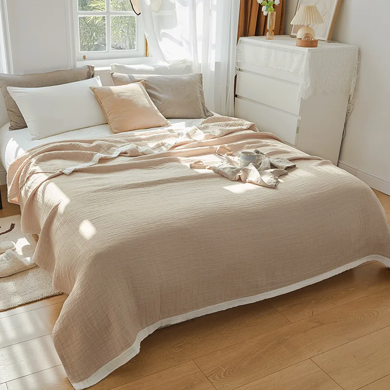 Beige muslin cotton blanket spread over a double bed, a white band along the hem