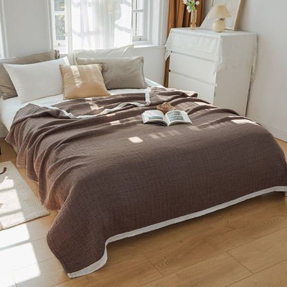 Deep brown muslin cotton blanket spread over a double bed, a white band along the hem