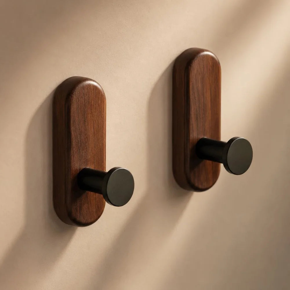 Close view of two walnut wall hooks with matte black pegs in warm side light
