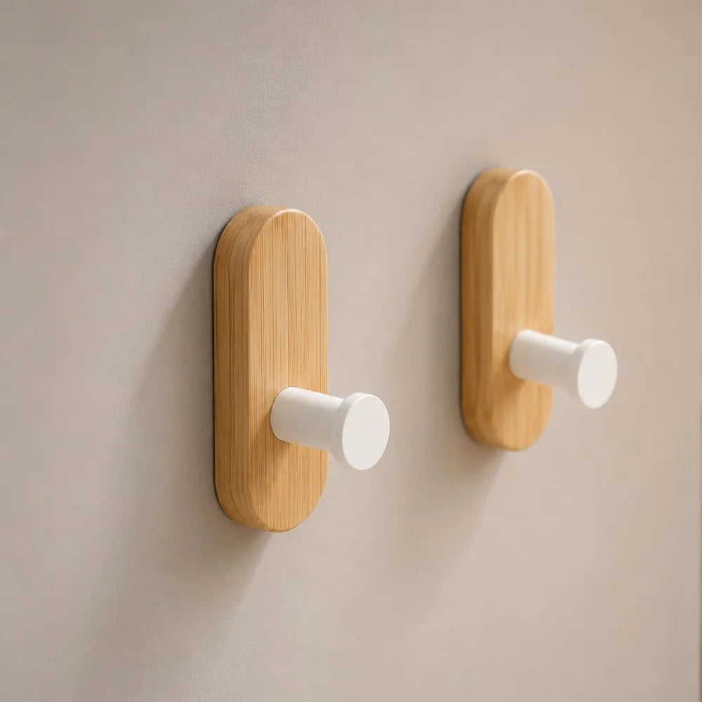 Close view of two light wood wall hooks with matte white pegs on a gray wall