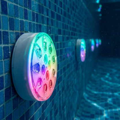 Close view of one rechargeable pool light on an underwater mosaic wall, a line of lit lights behind it