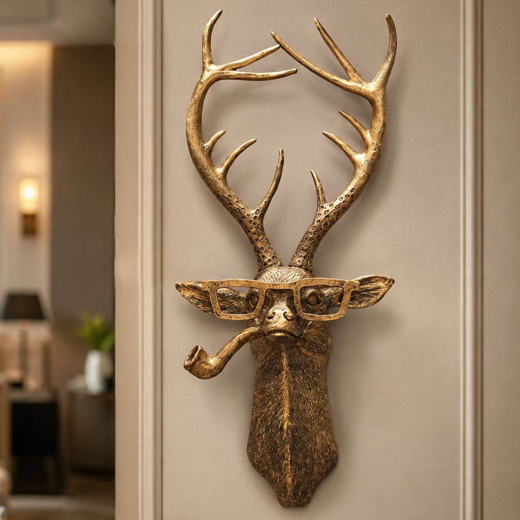 Close view of the gold-tone deer head sculpture with glasses and a pipe on a taupe wall
