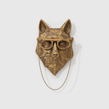 Fox head wall sculpture in antique gold-tone resin, with glasses and a fine chain, on a plain light gray wall
