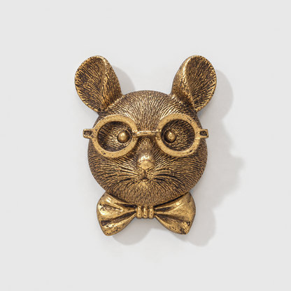 Mouse head wall sculpture in antique gold-tone resin, with round glasses and a bow tie, on a plain light gray wall