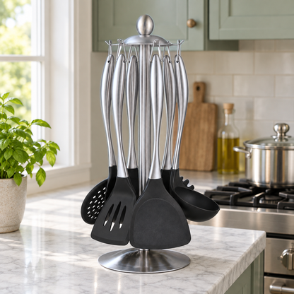 Silver cooking utensils hanging on a steel stand on a marble counter beside a gas range in a sage green kitchen
