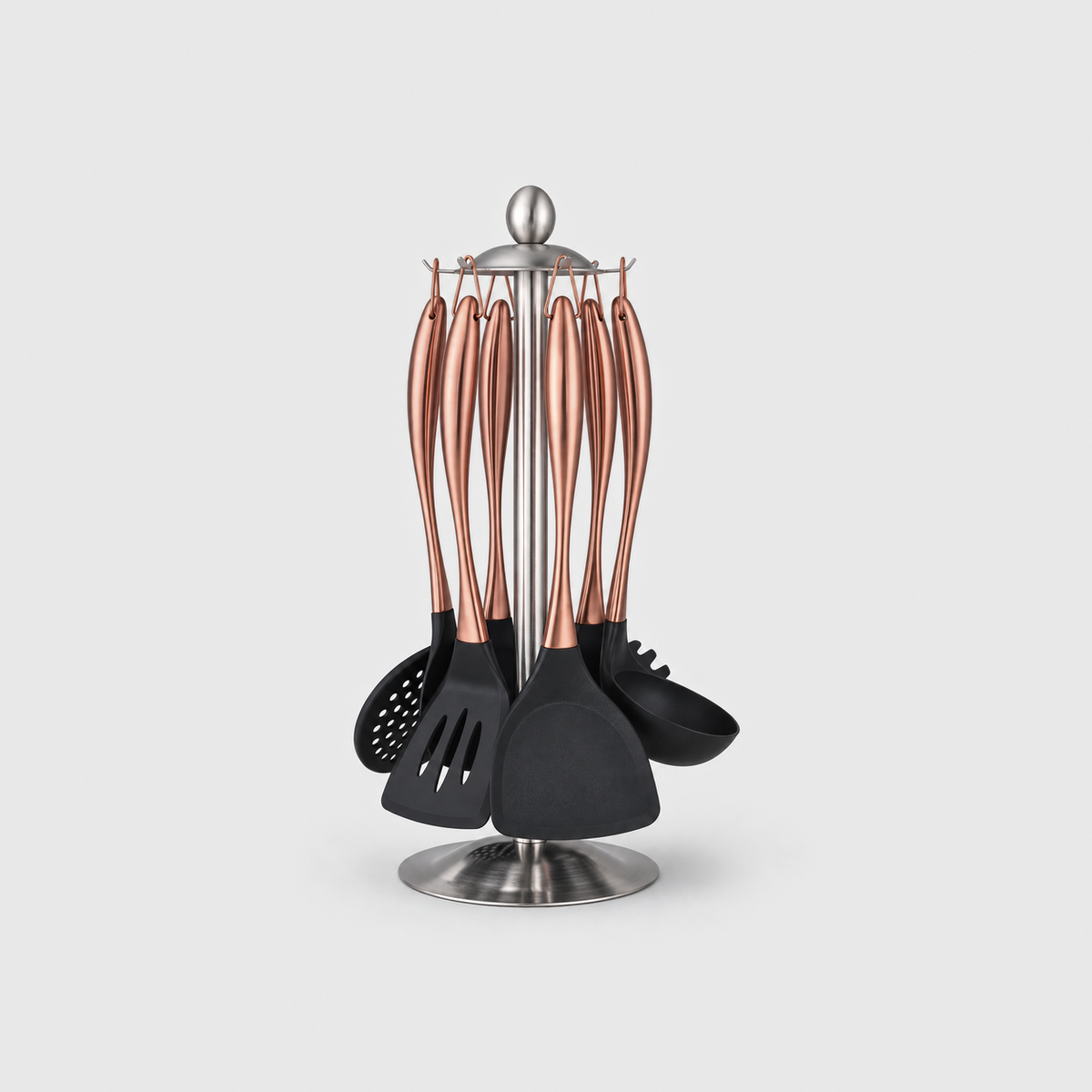 Rose gold-tone cooking utensil set hanging on a silver steel stand, on a light gray background