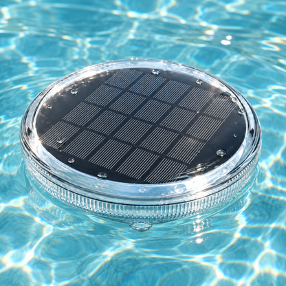 Close-up of a solar pool light floating in the sun, showing its solar panel and clear ribbed rim