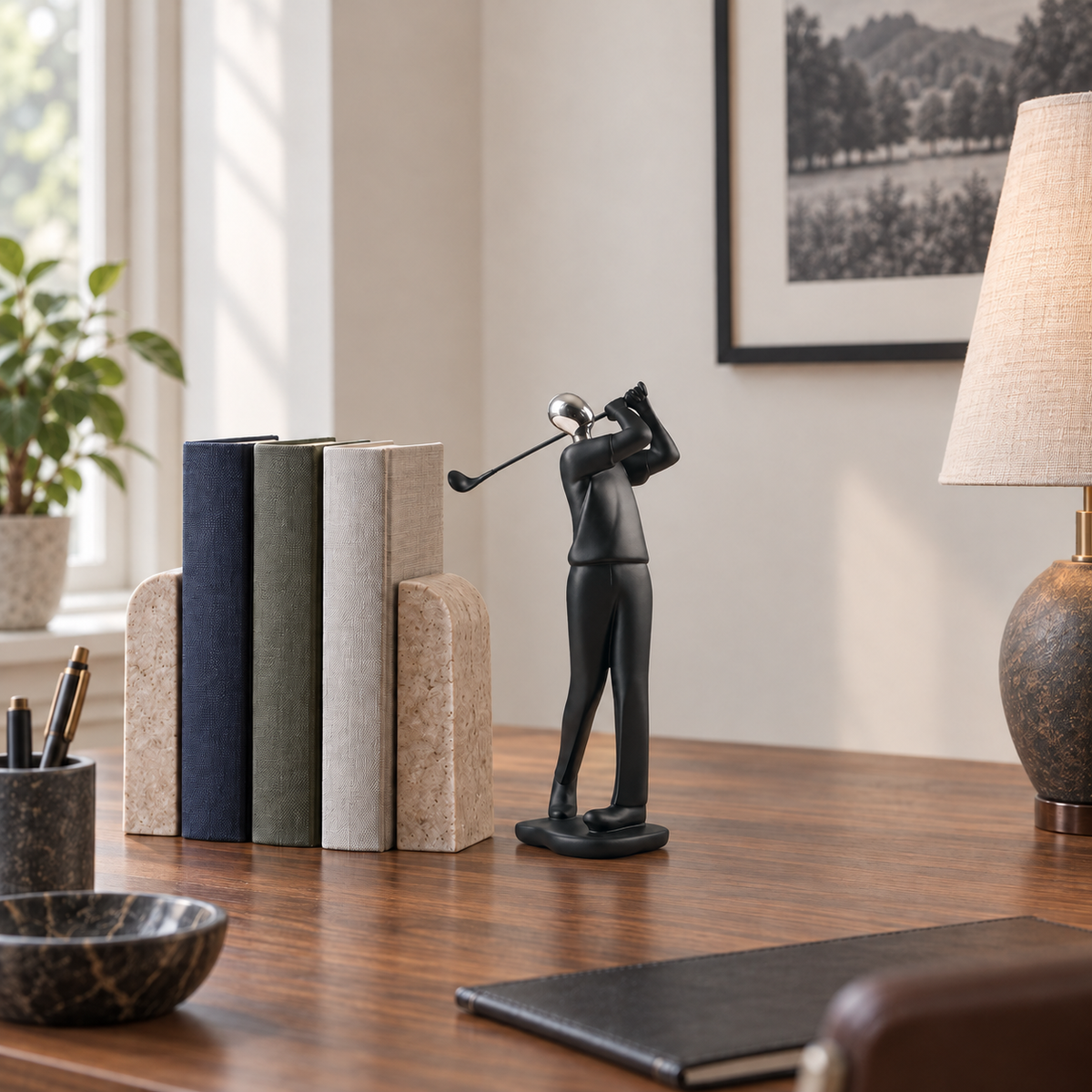 A black golfer sculpture with a silver head on a walnut desk beside a row of hardback books in a home study