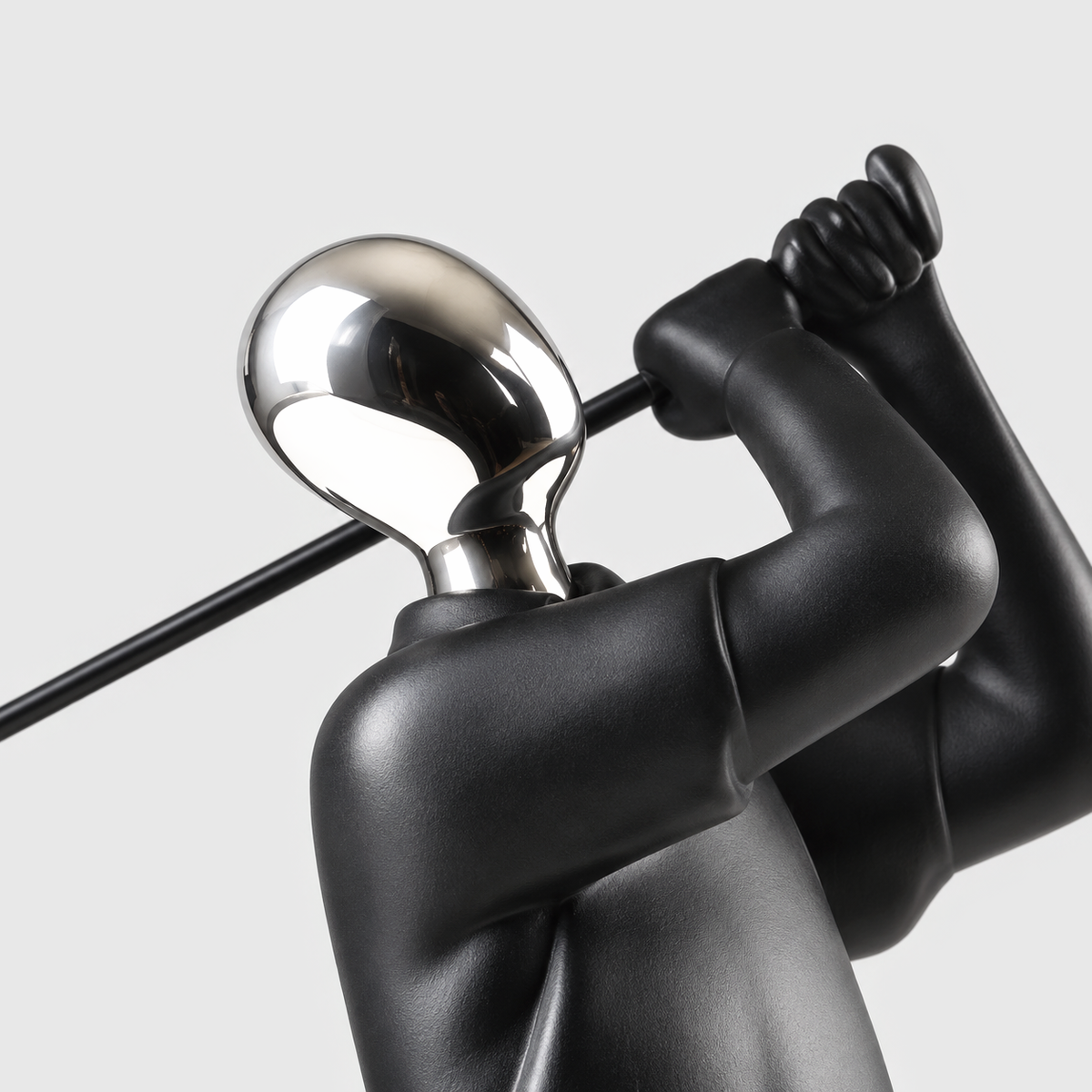 Close view of the mirror silver head and matte black shoulders of the golfer sculpture