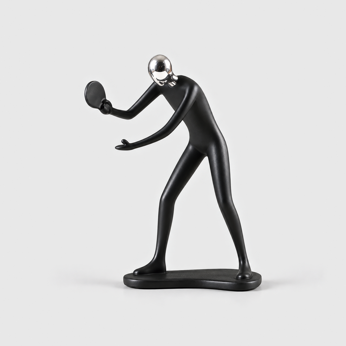 A matte black table tennis player sculpture leaning in with a round paddle, on a light gray background