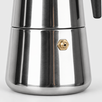 Close-up of the brass-colored safety valve on the polished steel base of a moka pot