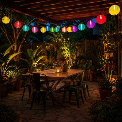 Multicolor lantern string lights hanging under a pergola above an outdoor dining table at night