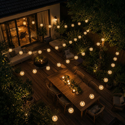 Aerial view of white solar lanterns lit around a deck and outdoor dining table at night