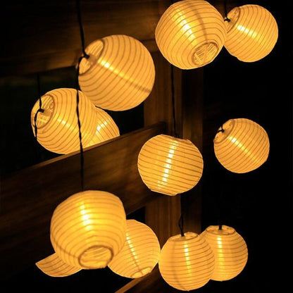White lanterns lit at night seen from below, with the black socket caps and the open lantern bases