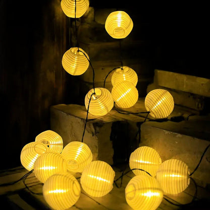 White solar lanterns lit and coiled across stone garden steps at night