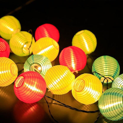 A pile of lit multicolor fabric lanterns in red, yellow and green