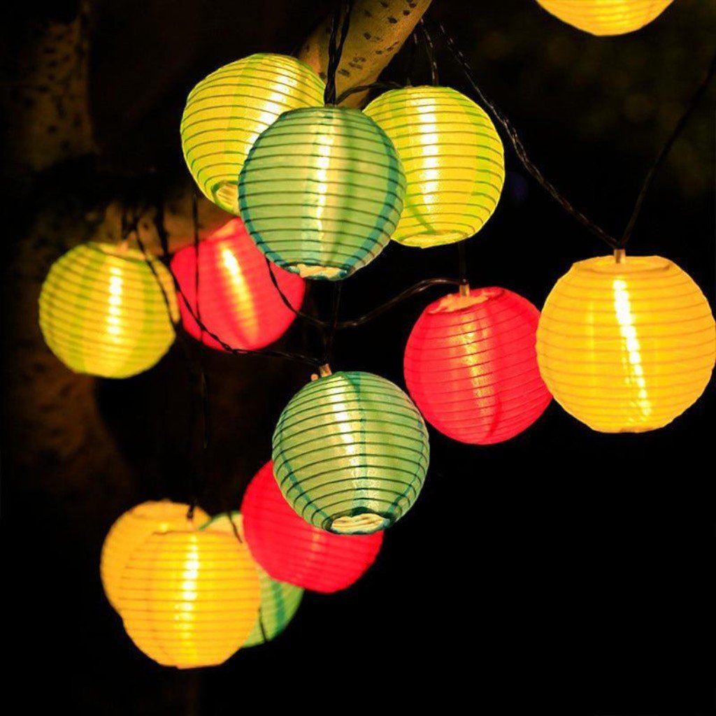 Multicolor lanterns hanging from a branch, lit in green, yellow and red