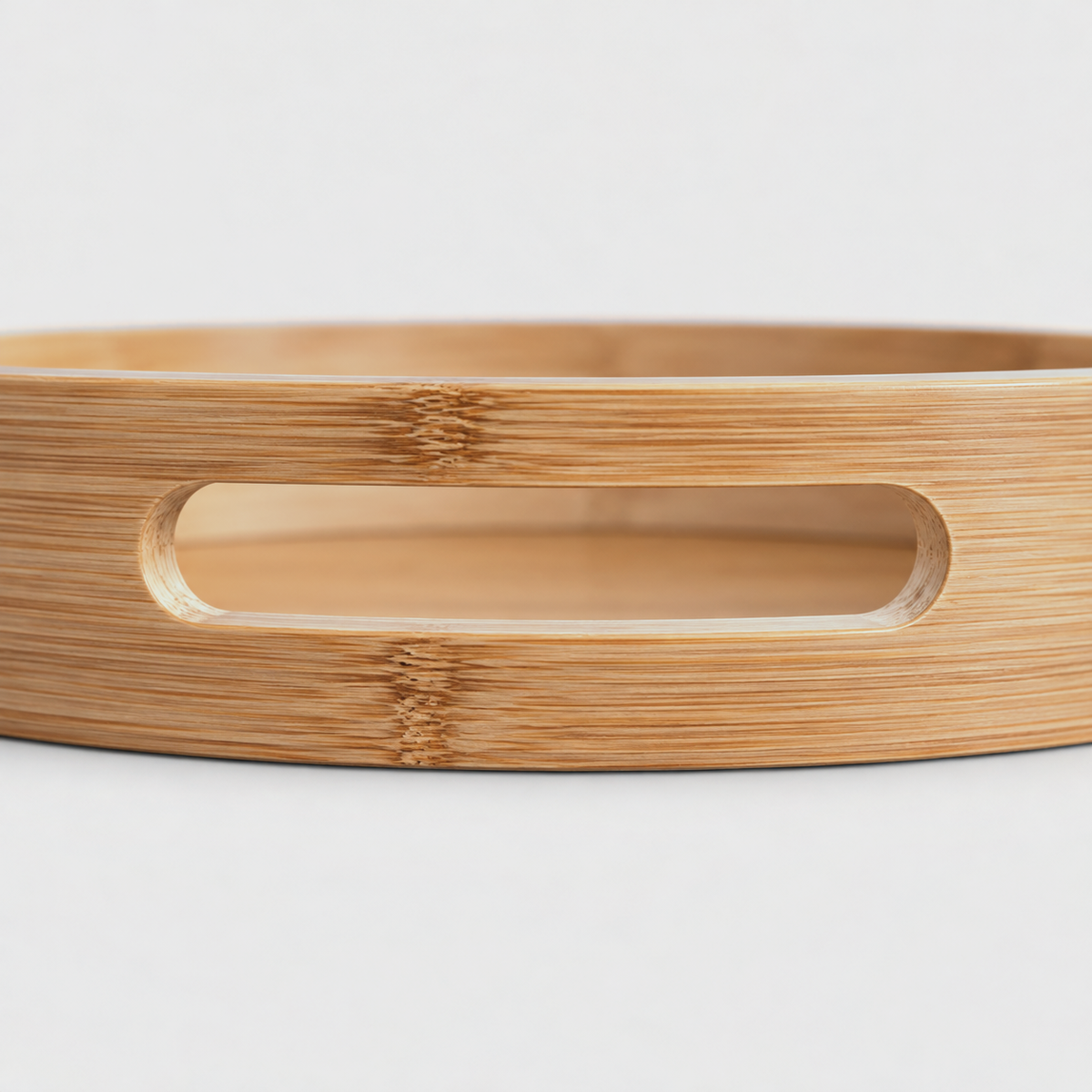Close-up of a slot handle cut through the smooth bamboo wall of a round serving tray
