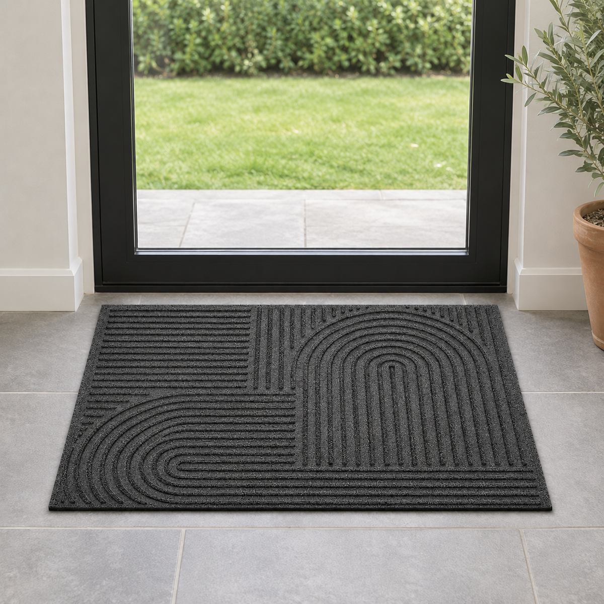 Black grooved doormat with a raised arc pattern on stone tiles inside a glass door to the garden