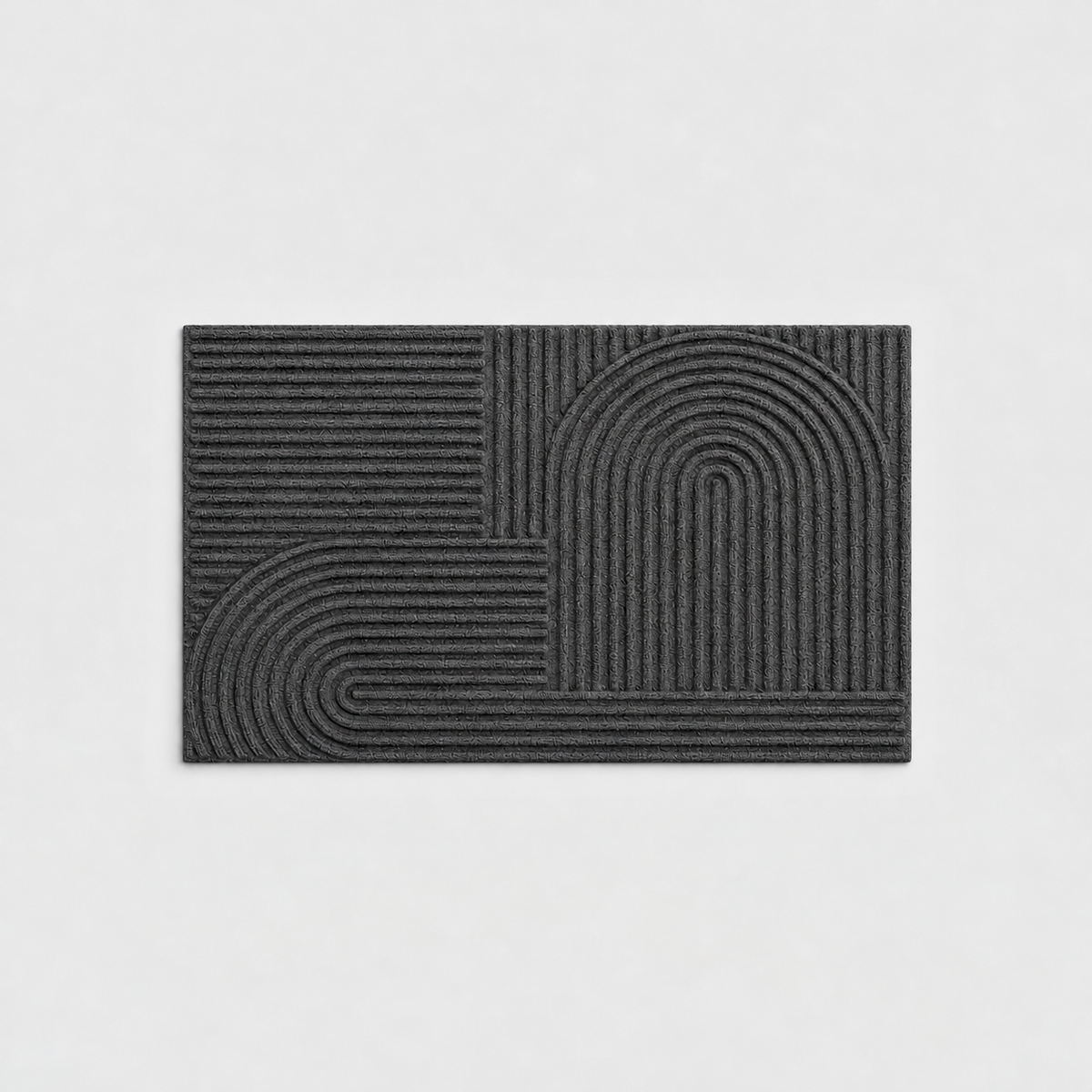 Black grooved doormat with a raised arc pattern, seen from above on a light gray background
