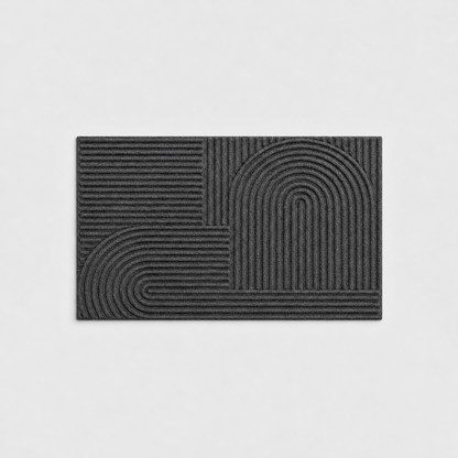 Black grooved doormat with a raised arc pattern, seen from above on a light gray background