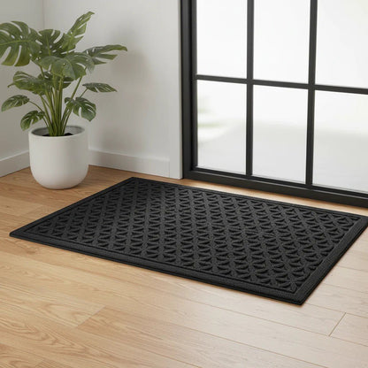 Black grooved doormat with a raised lattice pattern by a black-framed glass door and a potted plant