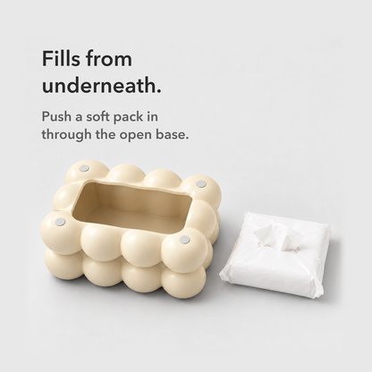 Cream bubble tissue box cover turned upside down to show its open base beside a soft pack of tissues, with the words Fills from underneath