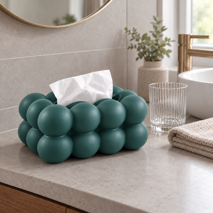 Teal bubble tissue box cover on a stone bathroom counter beside a folded hand towel